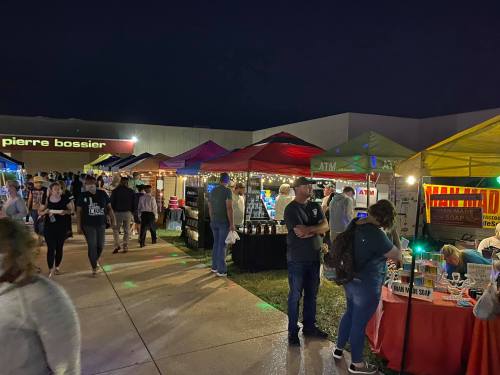 A lively night market scene with colorful tents, vendors, and people browsing various stalls.