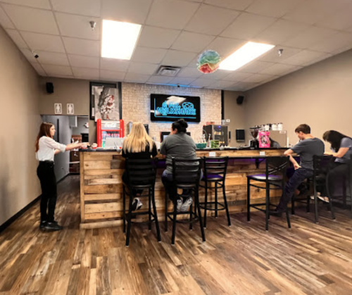 A cozy café interior with a wooden bar, patrons seated, and a colorful decoration hanging from the ceiling.