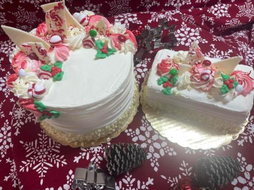 Two festive cakes decorated with red and white icing, candy canes, and chocolate accents, set on a holiday-themed background.