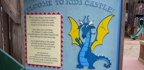 A colorful sign at Kids Castle featuring a friendly dragon named Devlin inviting children to play and explore.