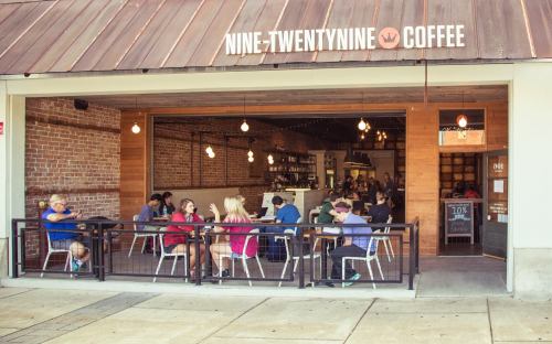 A bustling coffee shop with patrons seated at tables, enjoying drinks and conversation in a cozy, modern setting.
