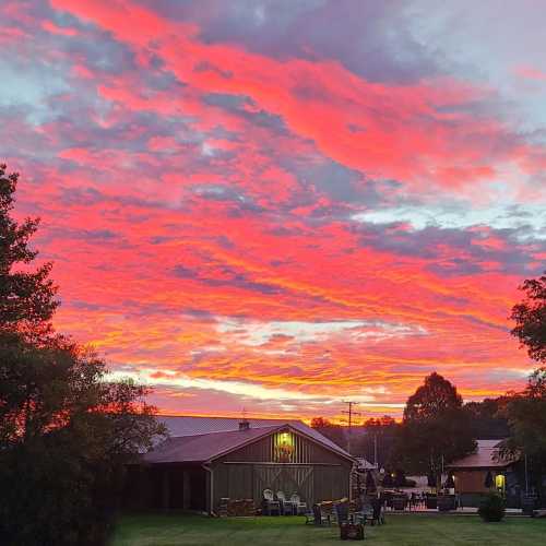 A vibrant sunset paints the sky in shades of pink and orange over a peaceful landscape with houses and trees.