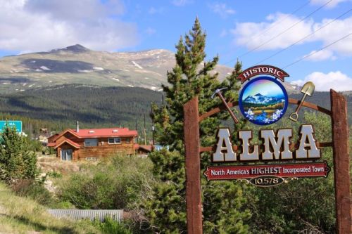 Sign for historic Alma, North America's highest incorporated town, with mountains and trees in the background.