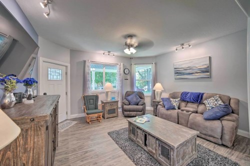 Cozy living room with a gray sofa, coffee table, and natural light from windows, decorated with blue accents.