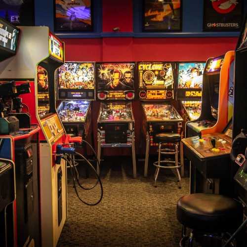 A retro arcade filled with pinball machines and classic video game cabinets in a vibrant, nostalgic setting.