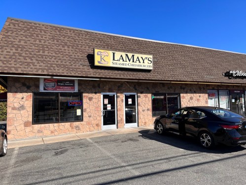 Exterior of LaMay's Steamed Cheeseburgers restaurant, featuring a stone facade and a car parked outside.