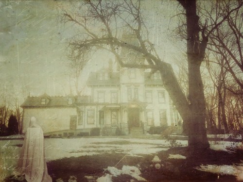 A vintage-style image of a large, old house surrounded by trees and snow, with a ghostly figure in the foreground.