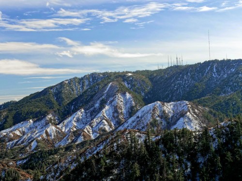Snow-covered mountains under a blue sky, with communication towers visible on the peaks.