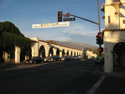 A street view featuring arched buildings, traffic lights, and a banner for an annual pumpkin social event.