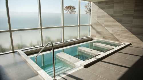 A modern spa with a small indoor pool and large windows overlooking a serene landscape.