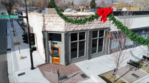 A festive building decorated with a wreath and bow, located at the corner of Carson Street, with a clear sky above.