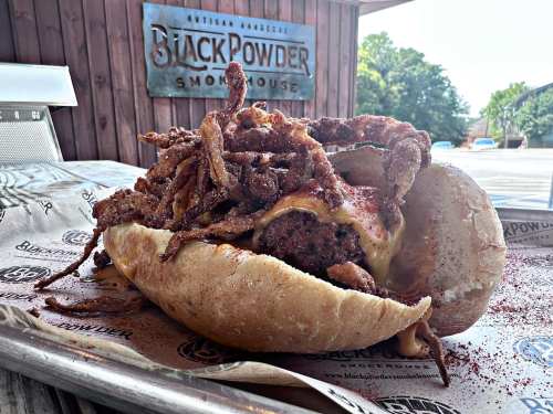 A hearty sandwich filled with beef, melted cheese, and crispy fried onions, served on a soft bun.