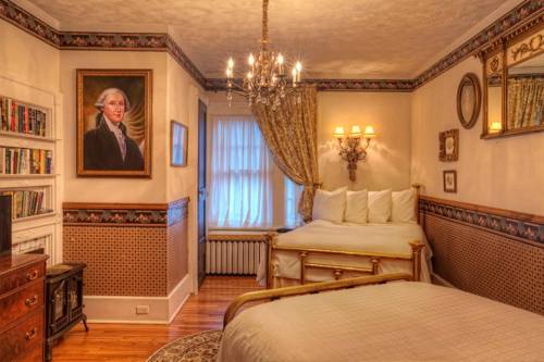 A cozy bedroom with two beds, a chandelier, a portrait on the wall, and warm decor.
