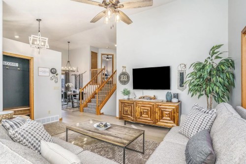Bright living room with a cozy sofa, wooden TV stand, and a staircase in the background, featuring modern decor.