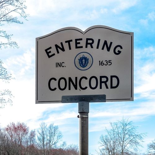 Sign reading "Entering Concord, Inc. 1635" against a blue sky with trees in the background.