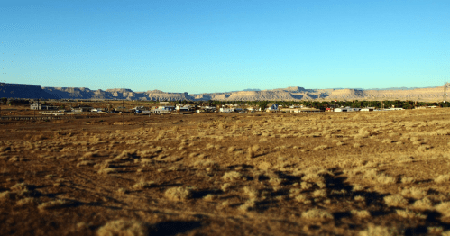 A small town nestled in a desert landscape, with mountains in the background under a clear blue sky.