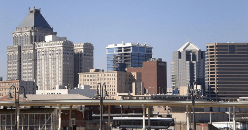 City skyline featuring a mix of historic and modern buildings under a clear blue sky.
