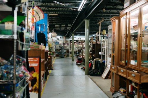 A wide aisle in an antique store filled with various vintage items and furniture on both sides.