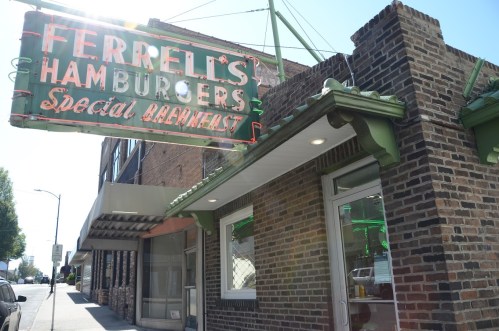 Exterior of Ferrell's Hamburgers, featuring a vintage neon sign and brick facade on a sunny street.