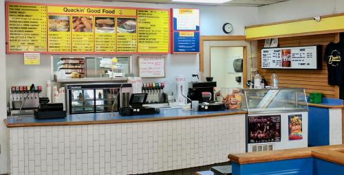 Interior of a fast food restaurant with a menu board, counter, and display cases for food and drinks.