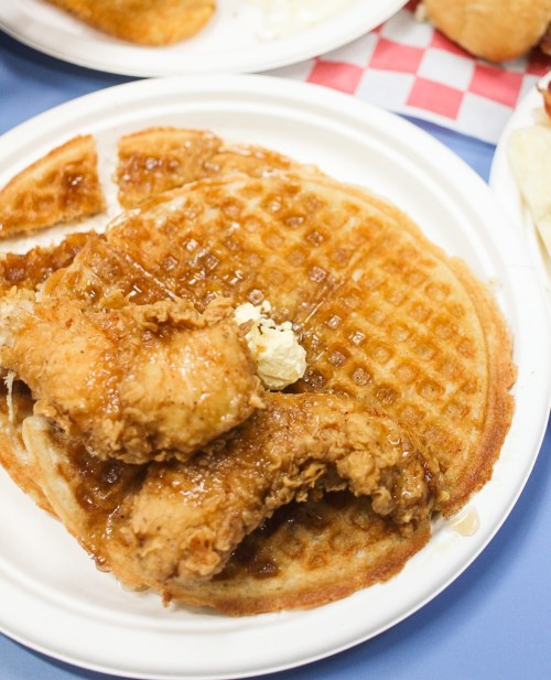 A plate featuring a golden waffle topped with fried chicken and drizzled with syrup.