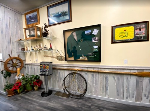 A wall display featuring nautical memorabilia, including a green jacket, photos, and decorative items.