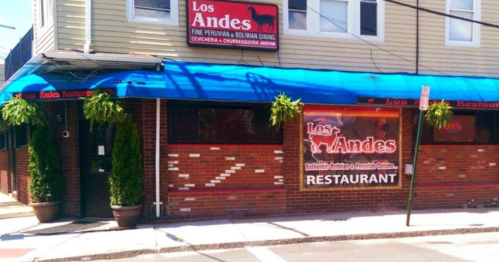 Exterior of Los Andes restaurant, featuring a blue awning, brick facade, and signage for Peruvian and Bolivian dining.