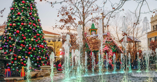 A festive scene featuring a decorated Christmas tree, a charming cabin, and colorful fountains in a holiday setting.