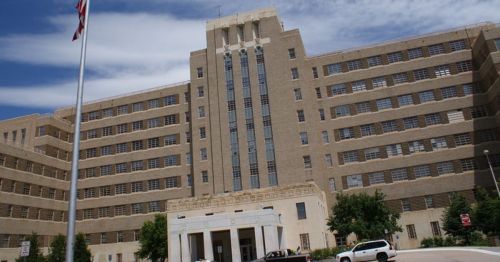 Historic building with a tall, art deco-style facade, featuring large windows and a central entrance, under a blue sky.