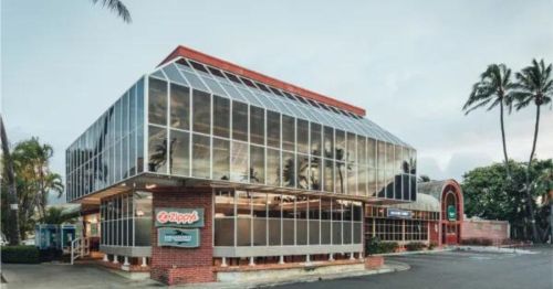 Modern glass-fronted building with palm trees, featuring a sign for "Zippy's" and a red brick facade.