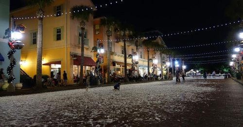 A festive street at night, decorated with lights and foam, with people enjoying the atmosphere.