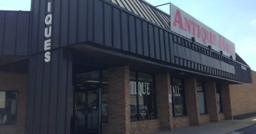 Exterior of an antique mall with large red signage and glass windows, showcasing a brick and metal building design.