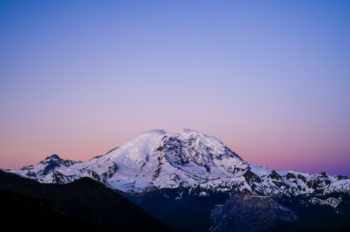 Snow-capped mountain at dusk, with a gradient sky transitioning from purple to pink.