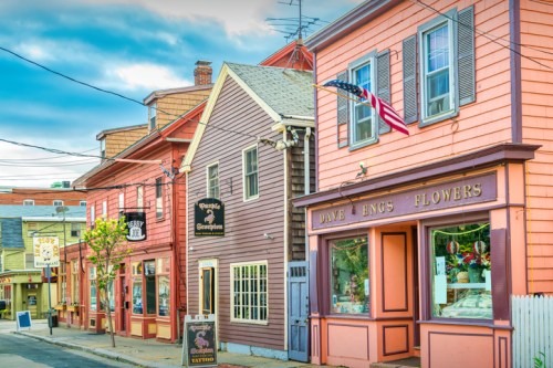 Charming street scene with colorful buildings, an American flag, and a flower shop in a quaint town.