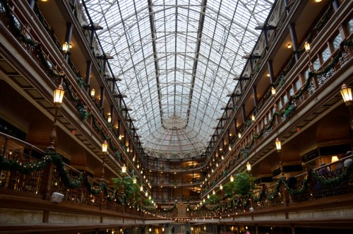 A grand indoor space with a glass ceiling, decorated with greenery and lights, showcasing elegant architecture.