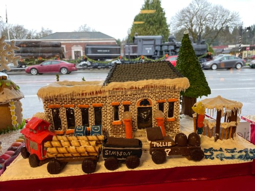 Gingerbread train and station scene with festive decorations, set against a snowy outdoor backdrop.