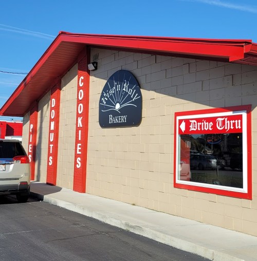 A bakery with a red roof and signage for pies, donuts, and cookies, featuring a drive-thru window.