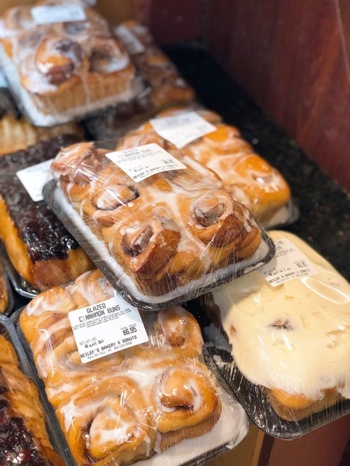 A display of glazed cinnamon rolls in plastic packaging, stacked on a shelf.