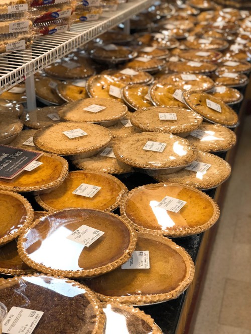 A display of various pies in clear packaging, arranged neatly on shelves in a store.