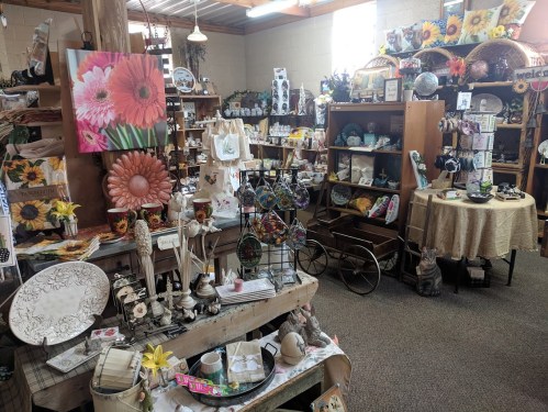A cozy shop filled with colorful crafts, home decor, and floral-themed items, showcasing a warm, inviting atmosphere.