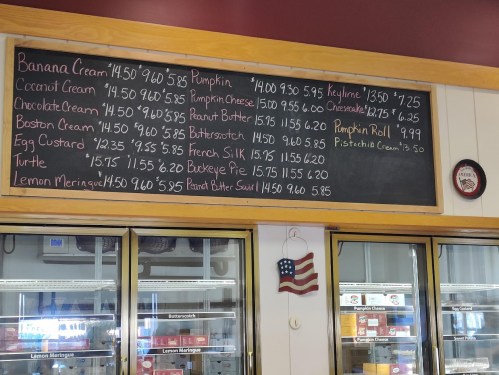 A chalkboard menu displaying various pie flavors and prices, including Banana Cream, Pumpkin, and Lemon Meringue.