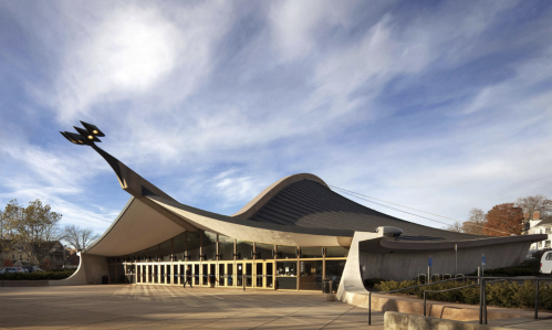 A modern building with a curved roof and unique architectural features, set against a blue sky.