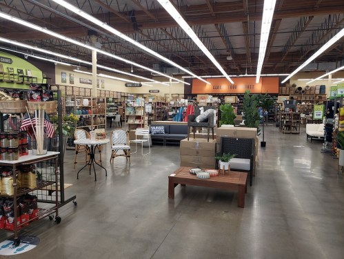 A spacious store interior filled with home decor items, furniture, and plants, featuring organized displays and bright lighting.