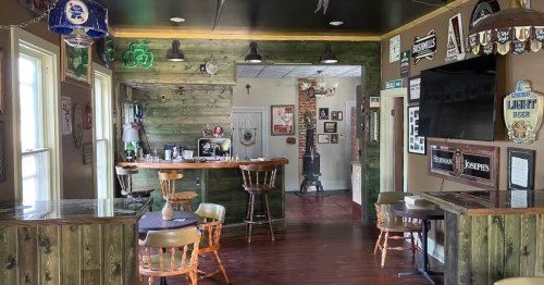 Rustic pub-themed interior of Finnebarre's in Nebraska, featuring a wooden bar, vintage signs, and beer banners.