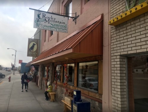Exterior of a seafood market with a sign reading "Rocky Mountain Seafood," featuring a sidewalk and nearby shops.