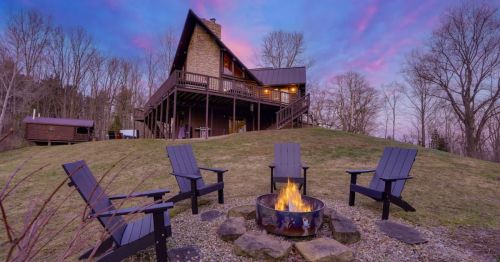 Sunset photo of the Juniper Cabin in Middlefield, Ohio, with a fire pit and chairs in the backyard