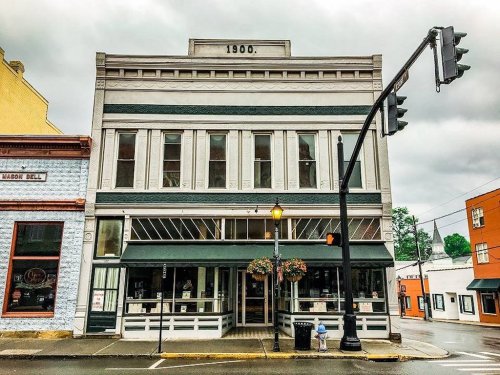 Historic building with a striped facade, large windows, and a streetlight in front, set against a cloudy sky.