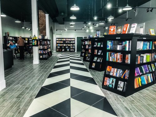 A modern bookstore interior with black and white patterned flooring and bookshelves filled with various books.