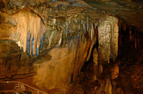 Stalactites and stalagmites in a dimly lit cave, showcasing unique rock formations and textures.