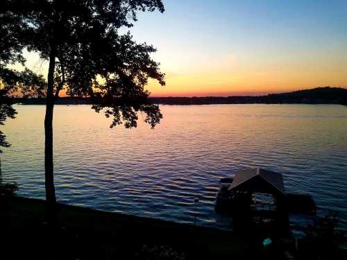 A serene lake at sunset, with calm waters reflecting vibrant colors and a small dock in the foreground.